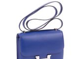 a blue handbag with a silver h on the handle