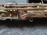 an old silver saxophone sitting on top of a table next to a cord
