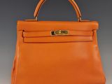 un sac à main en cuir orange avec des finitions dorées sur la poignée