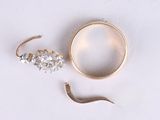 a gold ring and a pair of earrings on a white surface