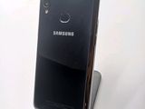 a black samsung phone sitting on a stand on a white surface