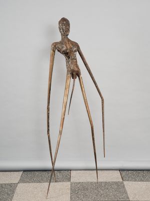 a bronze sculpture of a woman standing on a checkered floor