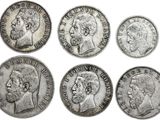 a group of five old silver coins with heads of men
