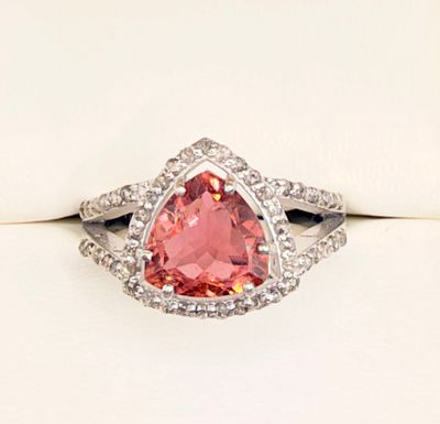 a close up of a pink diamond ring on a white surface