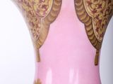 a pink and gold vase with gold decorations on it