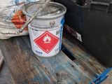 a bucket of paint sitting on a pallet next to other items