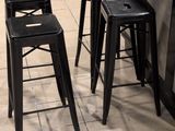 quatre tabourets noirs placés dans une cuisine, près d'un plan de travail