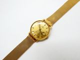 une image d'une montre-bracelet en or sur une surface blanche