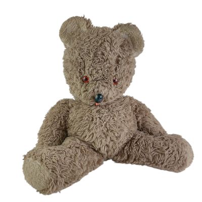 un ours en peluche marron assis sur une surface blanche