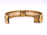a close up of a gold bracelet on a white surface