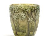 a green glass cup with trees on it on a white surface