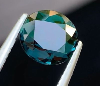 un gros plan d'un diamant bleu tenu par une pince