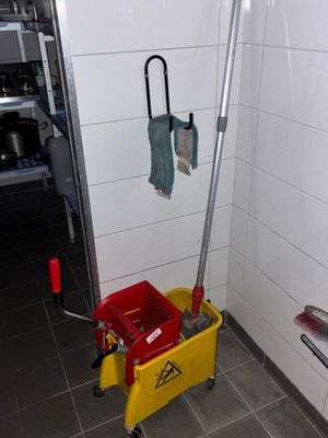 une serpillière et un seau dans un coin de la salle de bains