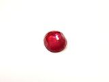 a close up of a red stone on a white surface