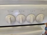 a close up of a white stove with four knobs