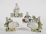 three figurines of people sitting on top of a white table