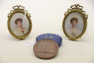 deux portraits miniatures représentant une femme et un penny posés sur une table