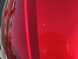 a close up of a red car with a reflection of a person on it