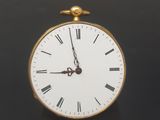 a small gold clock with roman numerals on it