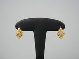 une paire de boucles d'oreilles en or et diamants posée sur un socle noir