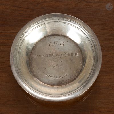 une assiette en argent posée sur une table en bois, sur laquelle figurent des inscriptions