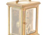 a small brass clock with a glass case on it