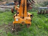 a tractor with a plow attached to it in the grass