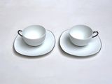 two cups and saucers sitting on a white table