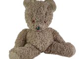 un ours en peluche marron assis sur une surface blanche