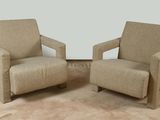 une paire de fauteuils rembourrés beiges dans une pièce où se trouve un tapis