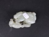 a small jade figurine of a frog on a black surface