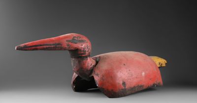 une photo représentant une statue d'oiseau rouge posée sur une table