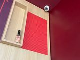 a bathroom with red walls and a wooden shelf with a bottle of perfume on it