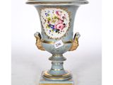 a blue vase with flowers on it sitting on a stand