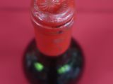 a close up of a bottle of wine on a pink background