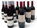 six bouteilles de vin sont alignées sur une surface blanche