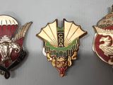 Trois insignes de formes et de couleurs différentes sont posés sur une table