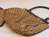 beige and black guccissi handbag sitting on a white surface