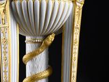 un vase blanc et doré surmonté d'un serpent