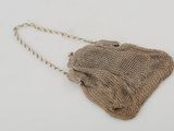 a close up of a purse on a white surface with a chain