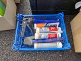 a blue basket with some glue, glue, glue gun, and other items in it