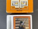 une image représentant une console de jeux Nintendo posée sur une table, accompagnée d'une boîte