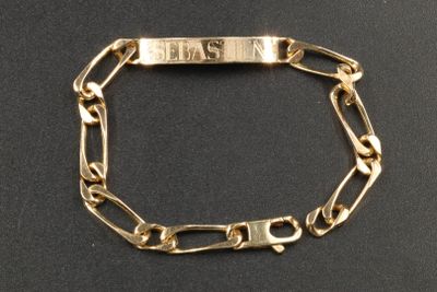 un gros plan d'un bracelet en or orné d'une plaque portant un nom