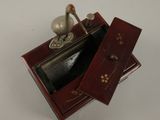 a small red box with a silver bird on top of it
