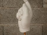 a white sculpture of a hand on a wooden stand