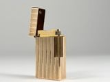 a close up of a gold lighter on a white surface