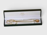 a close up of a necklace in a box on a white surface