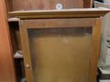a wooden cabinet with a glass door on top of it