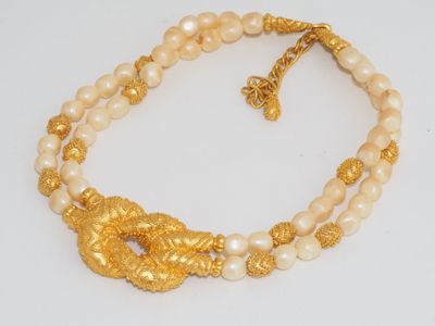 a close up of a necklace with pearls and gold
