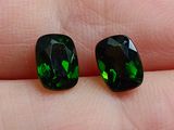 une paire de tourmalines vertes posées sur le doigt d'une personne